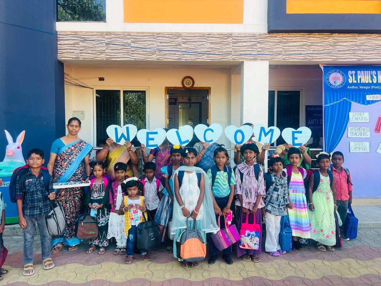 Students and teachers holding WELCOME letter cutouts at the school entrance