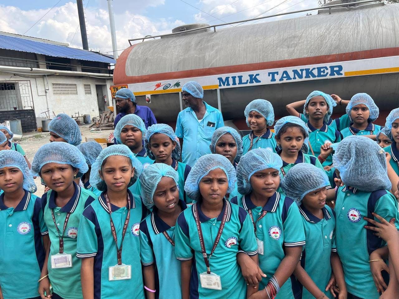 Group of students in hairnets standing in front of a milk tanker during the dairy plant tour