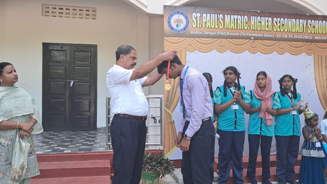 Founder presenting a gold medal to a top-ranking student on stage