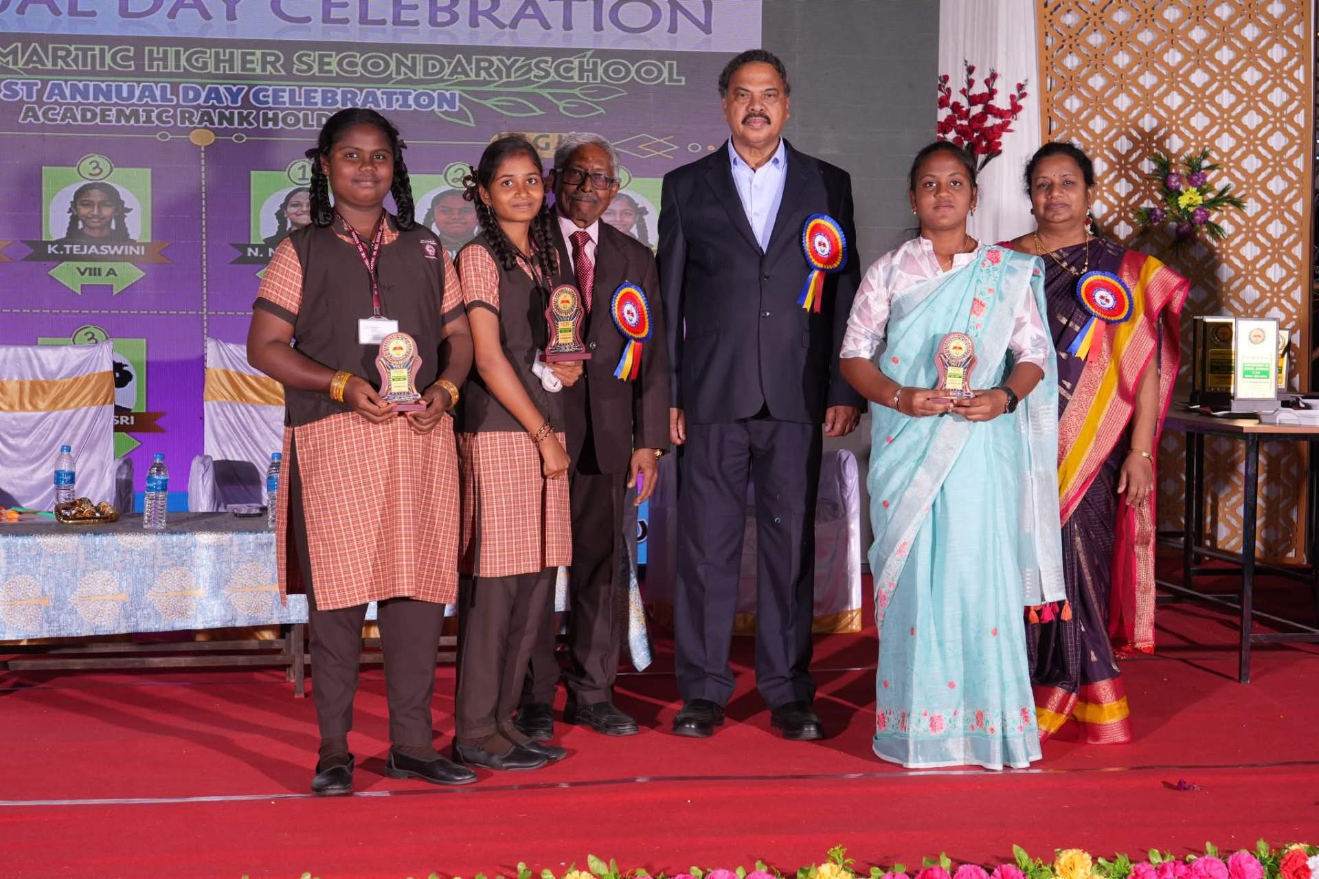 Academic rank holders receiving trophies from chief guests at the school's Annual Day Celebration