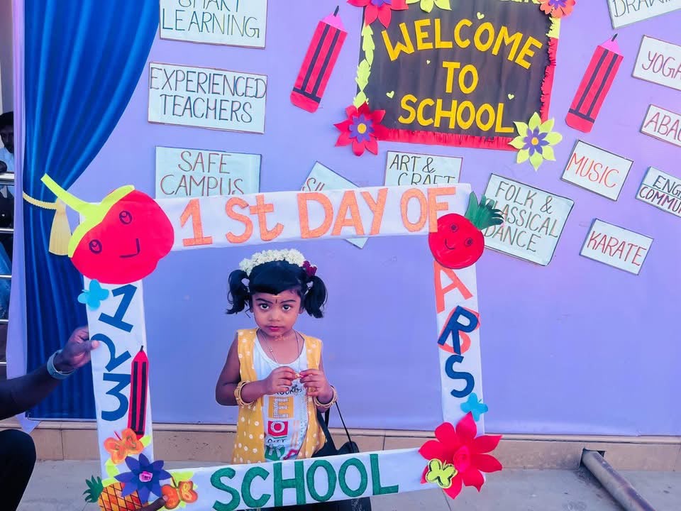 Young child posing in a colourful photo frame on her first day of school